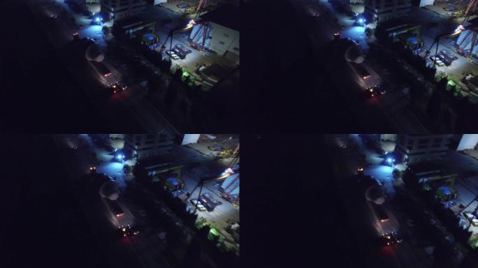 夜间无人机拍摄了一个大型物流车队——在工业区用卡车进行大型物体运输作业