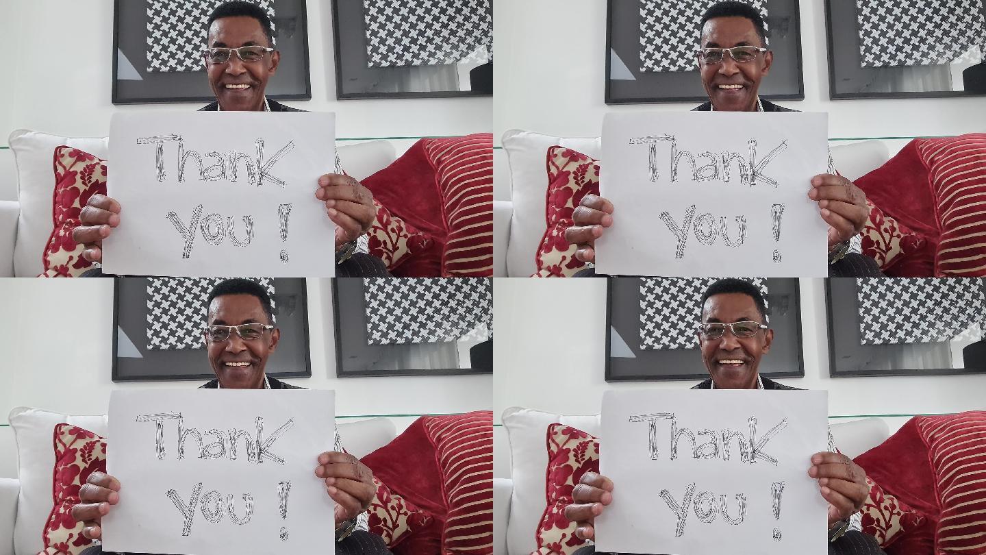 资深男士在视频通话中展示写有“谢谢”的论文-网络摄像头视角