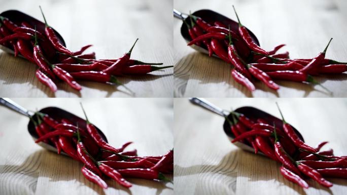 用勺子舀一堆新鲜的红辣椒，背景是木头