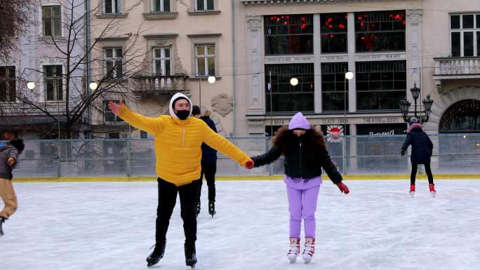 一对正在享受圣诞节假期的年轻夫妇在城市户外滑冰