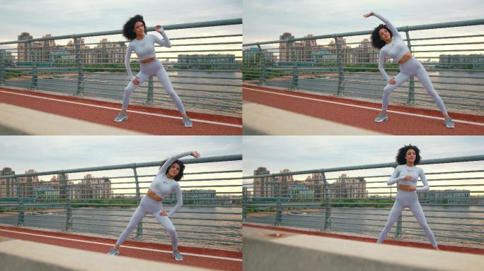 一位美丽苗条的女性跑步者，黑色卷发，穿着白色运动服，在高桥上的跑道上伸展身体，背景是城市景观