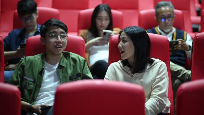 亚裔中国年轻夫妇在电影院等待电影放映的同时，享受彼此的陪伴