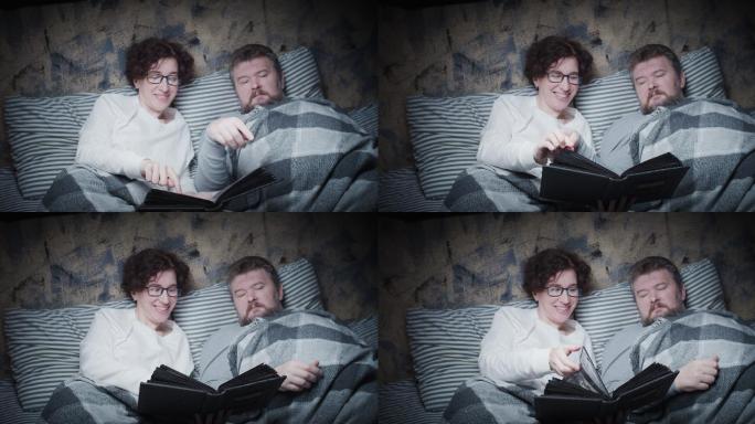 一对成熟的夫妇在床上看旧相册