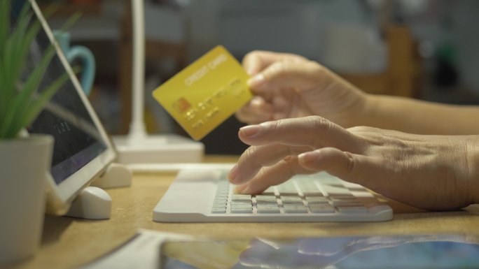 双手填写信用卡详细信息，以便在夜间进行家庭付款或在线购物，这是一种生活方式概念。