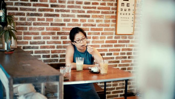 在咖啡馆喝冰绿茶拿铁的亚洲女人。