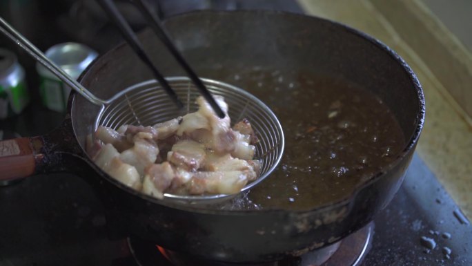 一位厨师在使用油锅炸猪五花肉