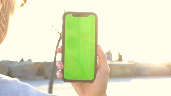在公园里手持手机，屏幕为绿色
