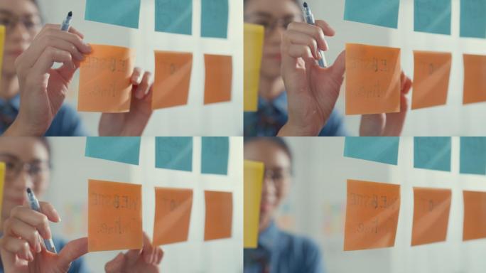 年轻的女商人在彩色的便签上写字，在创意办公室开发商业项目。