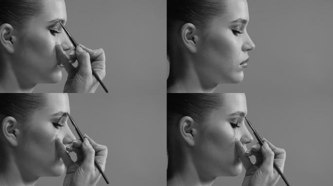 一位化妆师画一条眉毛时一张女孩脸的特写侧视图。黑白视频。