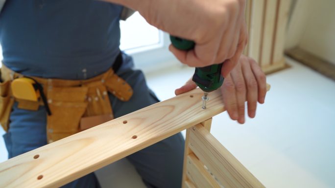 无法辨认的木匠用电动螺丝刀连接厨房家具的特写镜头