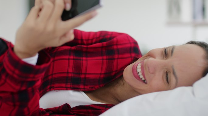 年轻女子在床上玩手机，放松身心