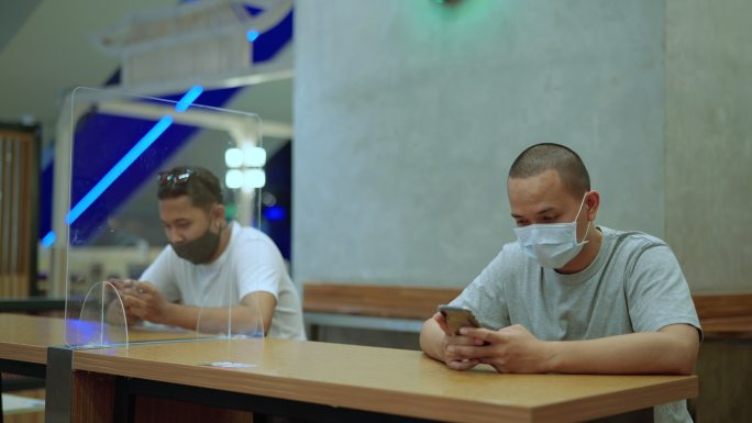 年轻的亚裔男子在使用智能手机和社交距离前清洗消毒病毒