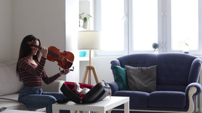 小提琴手从提琴袋中取出小提琴和琴弓，开始在家里练习演奏。