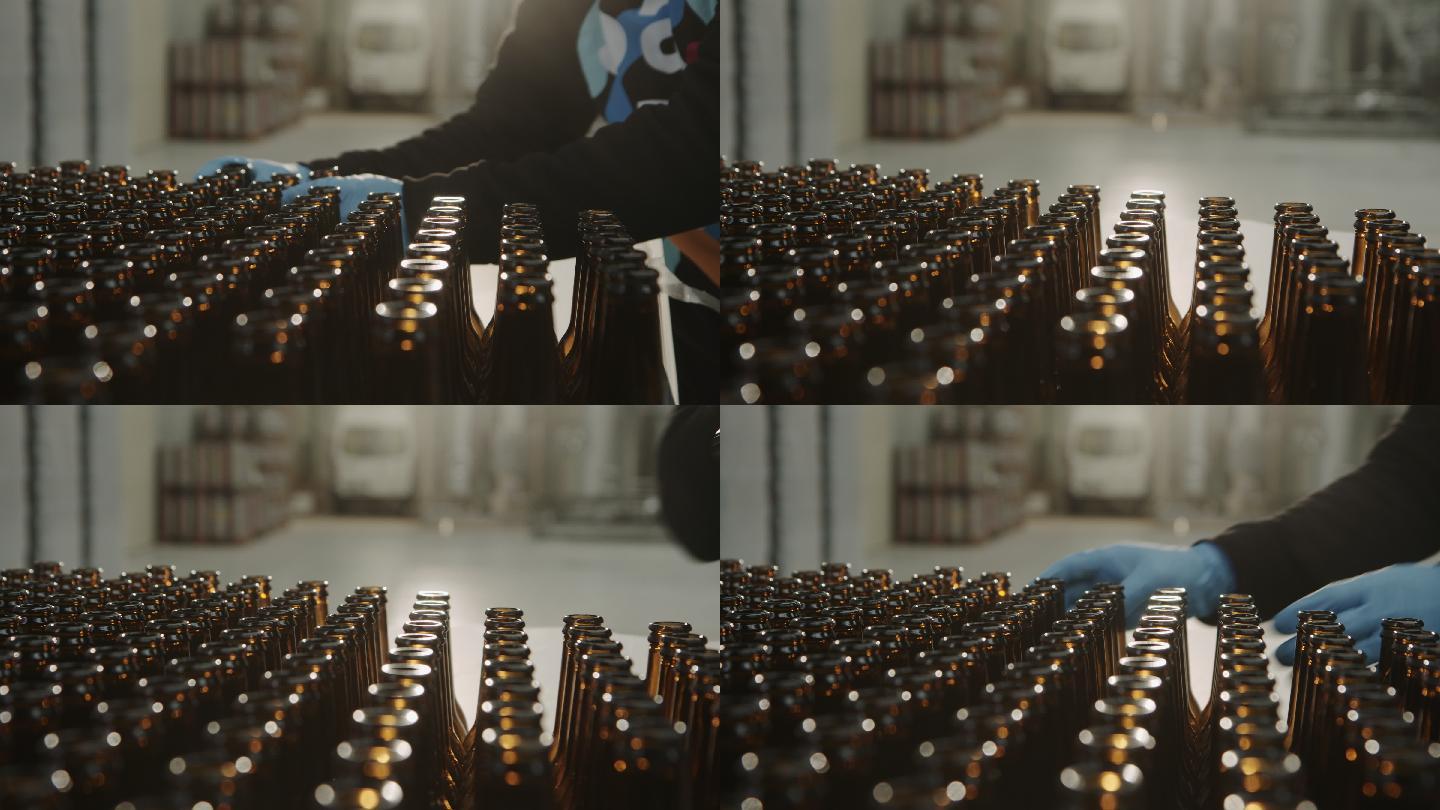 手工工人将一个空啤酒瓶放在工厂的输送机上生产啤酒。瓶子是焦点。男人的手特写镜头。生产的概念