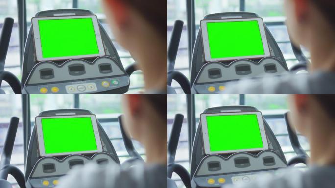 高清慢动作：女性在健身房锻炼，看着绿色屏幕的数字平板电脑