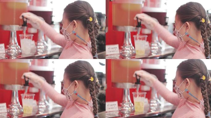 一个亚洲小女孩在餐馆的冷饮机里倒酒