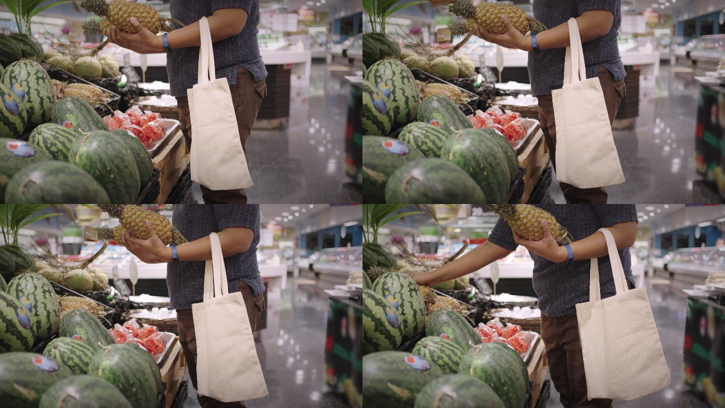 胖乎乎的男人拿着布袋在农产品通道上挑选菠萝