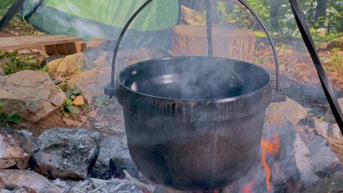 POV：在篝火上用铸铁锅煮炖菜的人