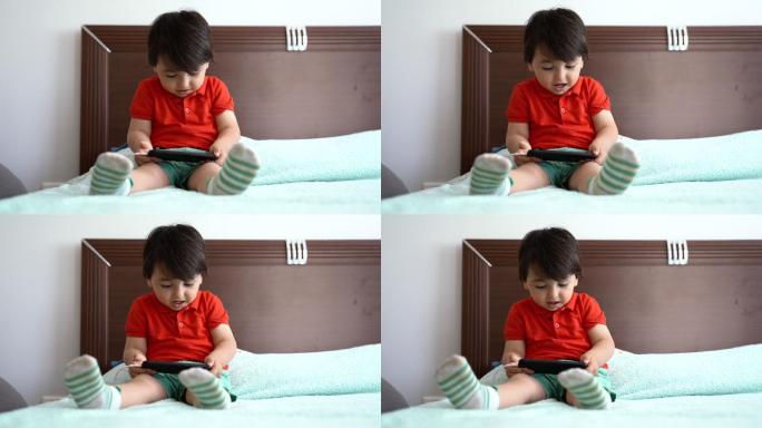 坐在床上玩智能手机的小男孩，4K视频片段