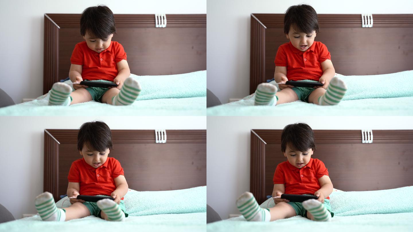 坐在床上玩智能手机的小男孩，4K视频片段