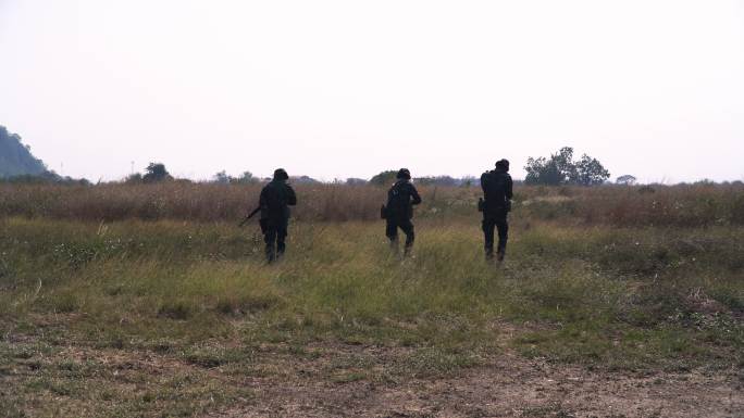 一群全副武装的士兵在草地上巡逻