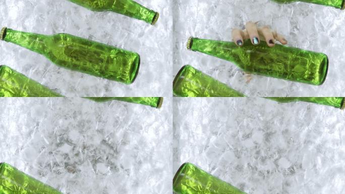 一个女人的手从一个冰容器里拿出一个绿色的啤酒瓶