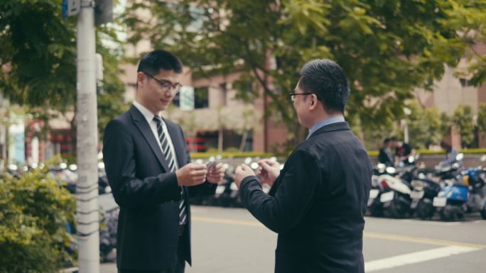 两名亚洲商人在街上交换名片