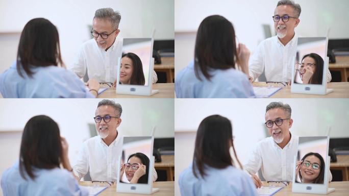 亚裔华裔工作高级男子在眼镜店向正在镜子前试镜的女性顾客解释