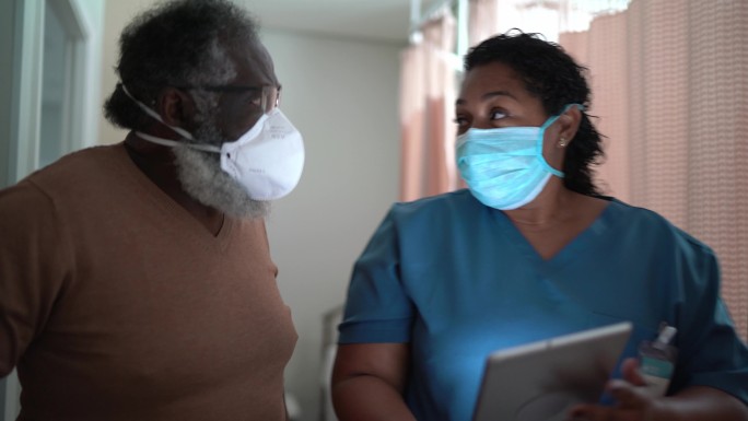 护士在医院医疗预约期间与患者交谈——戴防护口罩