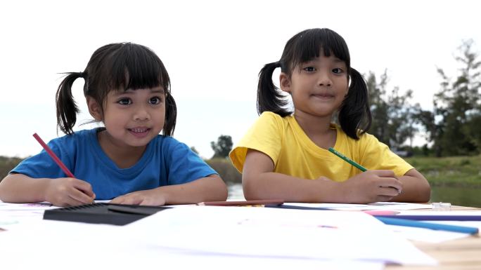 兄弟姐妹用彩色铅笔在纸上画卡通的场景，教育背景