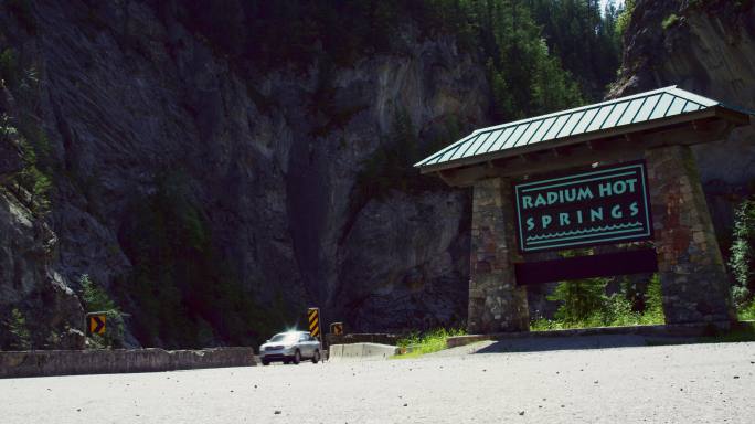 在加拿大不列颠哥伦比亚省的加拿大落基山脉，阳光明媚的日子里，汽车和其他车辆驶过“镭温泉”的标志