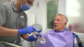牙医拿着假牙，在牙医办公室与患者交谈视频素材