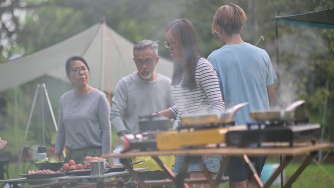 亚裔华人兄弟姐妹在露营时为家人准备早餐