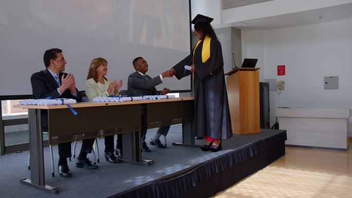 非裔美国女研究生在获得大学文凭时与董事会成员握手