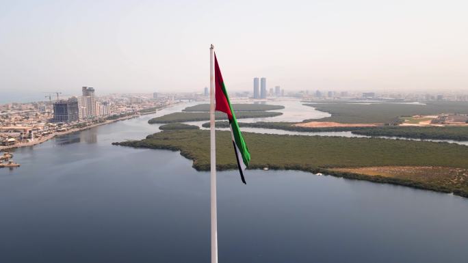 阿联酋国旗和哈伊马角酋长国空中城市景观地标性天际线，耸立在阿联酋北部的红树林和小溪之上