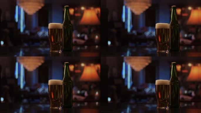 在烛光照亮的黑暗房间里，一杯啤酒和一个玻璃瓶并排放在吧台上