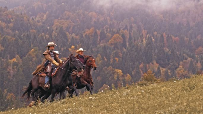 斯洛·莫骑着奔马的两个牛仔和牛仔女孩