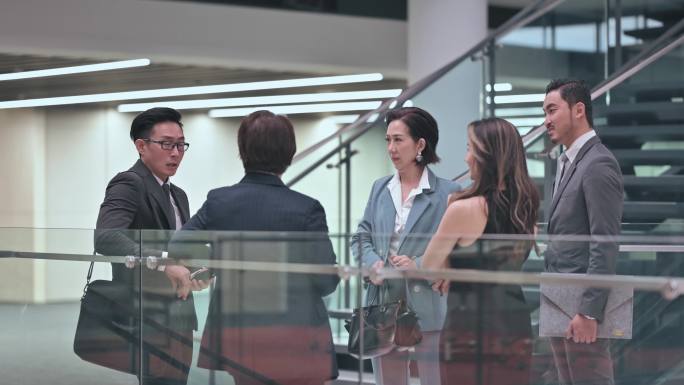 亚裔华裔商务装同事下班后在办公楼走廊交谈