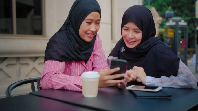 伊斯兰女性朋友一边看手机上的视频流，一边笑