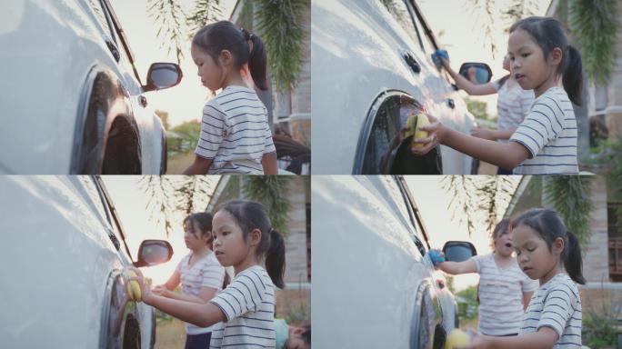 日落时分，亚洲小女孩和妹妹在家里用海绵和阳光一起帮父母洗车。