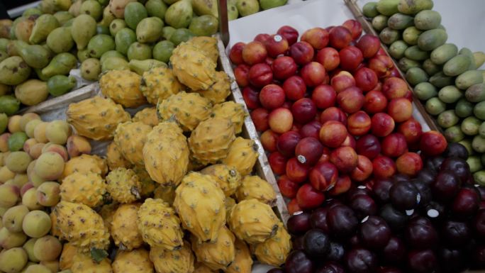 农贸市场上鲜美多彩的水果特写镜头和抓着两个火龙果的面目全非的女人——生活方式