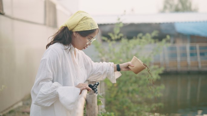 在养鱼场喂鱼的妇女