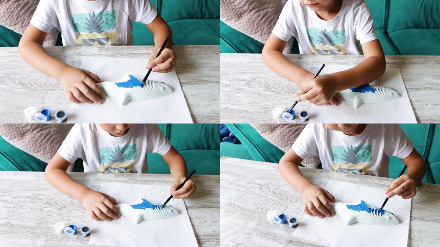 孩子用刷子和蓝色蛋彩画画石膏鲨鱼