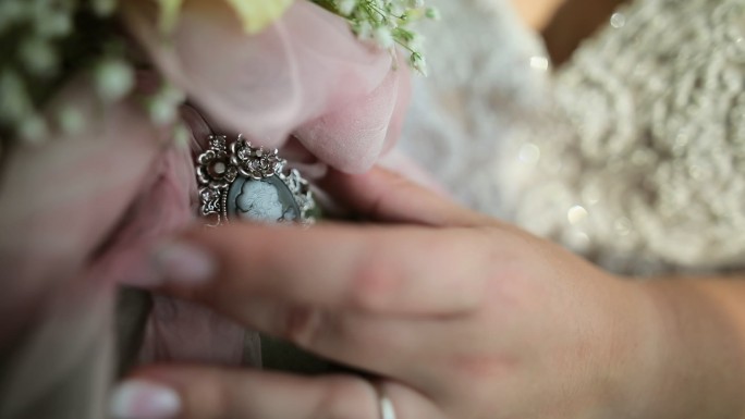 新娘手上戴着戒指，手上拿着带奖章的婚礼花束
