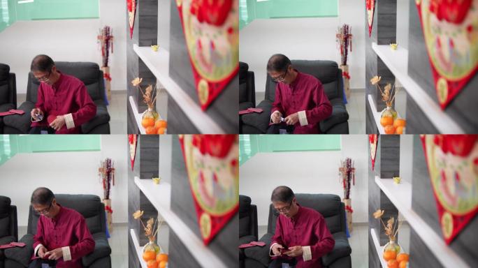中国农历新年期间，亚洲华人微笑老人在客厅把钱放进红包