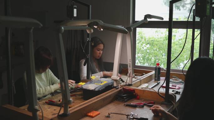 亚裔中国女大学生在工作台上并肩打造珠宝设计