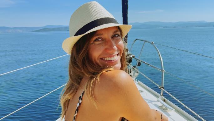 阳光明媚的日子里，一位在游艇上晒日光浴的女士一边说话一边微笑