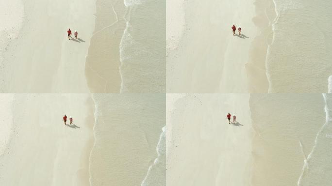 4k无人机拍摄的一对情侣在海滩上轻松漫步的画面