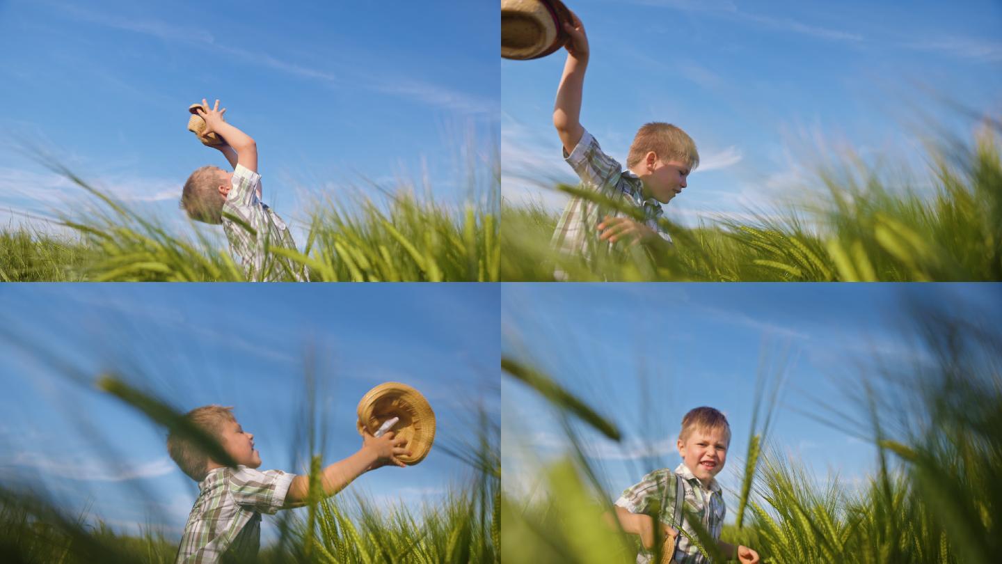 站在田里向空中扔帽子的男孩