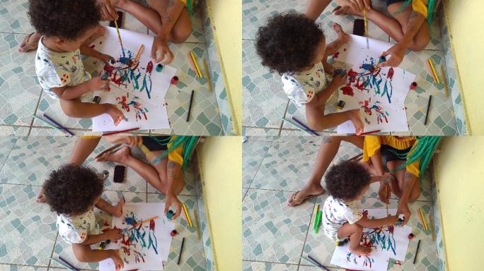 母亲和她的手脏的男婴在家里画画取乐